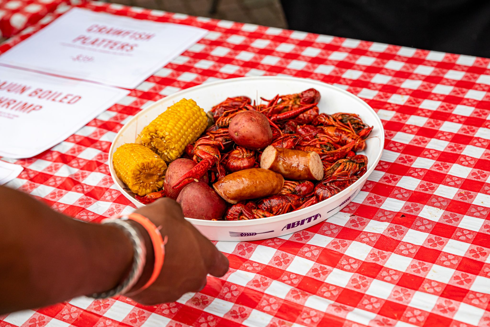 Crawfish platter with corn, potatoes, and sausage on a checkered table