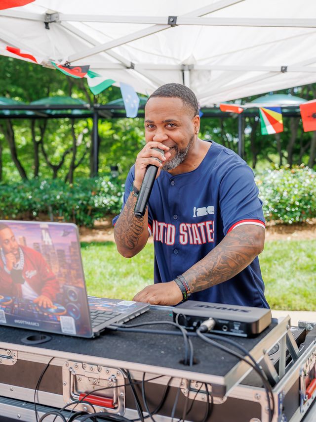 DJ on the mic under a tent at the World Cup themed tenant event